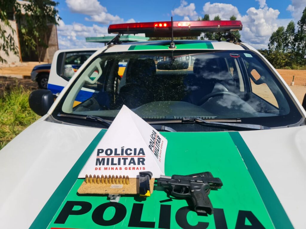 Arma de fogo e munições em cima do capô de viatura com símbolo da Polícia Militar representando apreensão de arma em Santana de Pirapama - MG