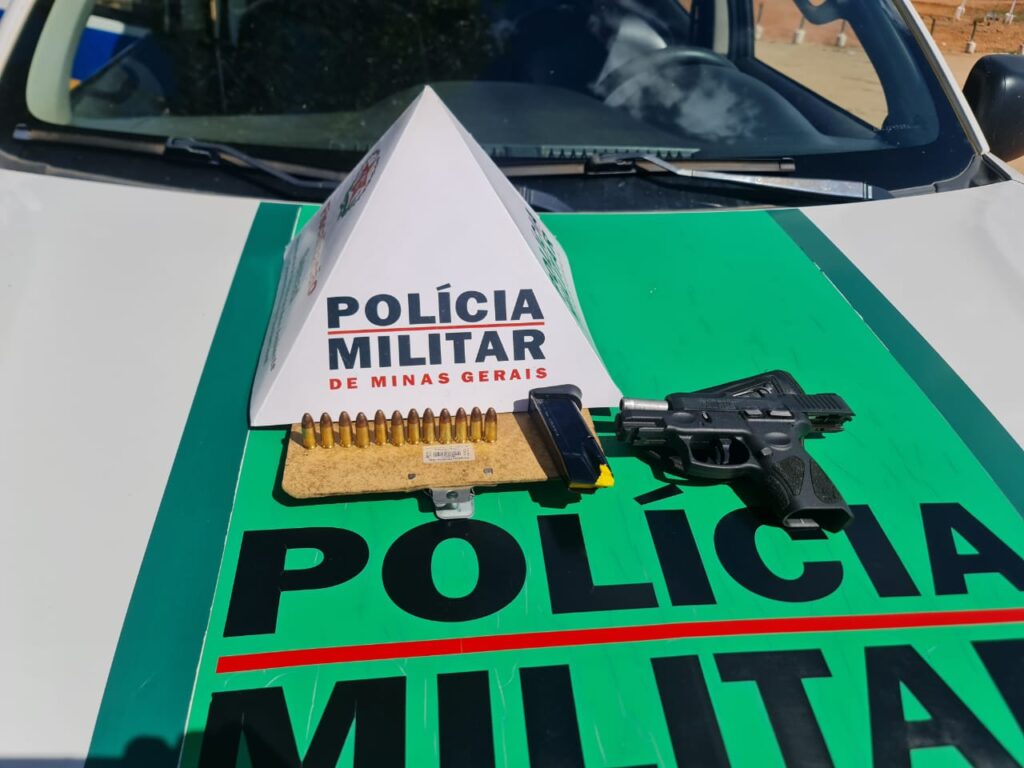 Arma de fogo e munições em cima do capô de viatura com símbolo da Polícia Militar representando apreensão de arma em Santana de Pirapama - MG