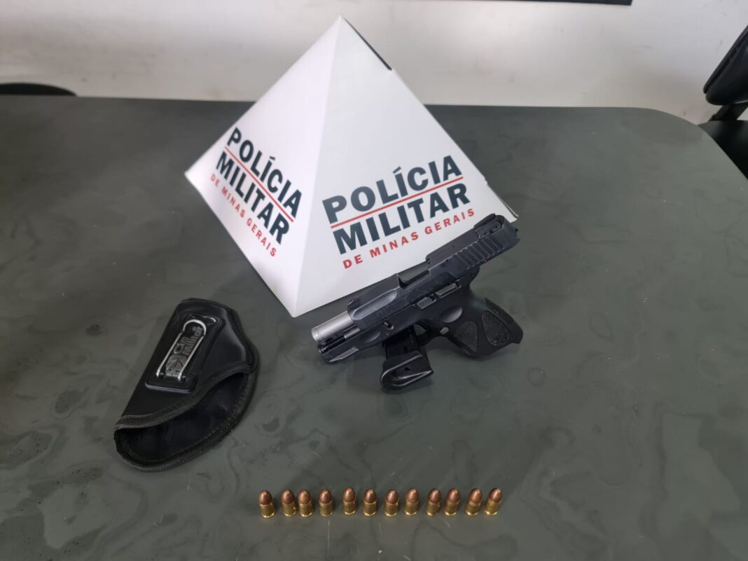Arma de fogo e munições em cima da mesa com símbolo da Polícia Militar representando apreensão de arma em Santana de Pirapama - MG